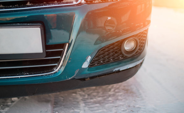 Scratches and cracks on the bumper of the green car. Broken bumper after a car crash. scratches and cracks in the car. winter snow. © Dima