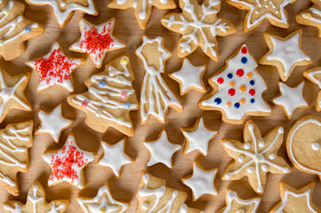 Homemade Christmas cookies in the shape of star, fir tree and snowflake with white glaze on wooden table background, closeup
