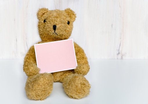 Teddy bear holding pink greeting card
