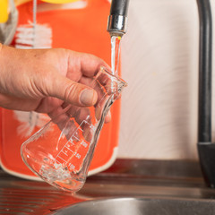 A man pours tap water into a glass flask.