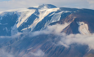 Snow-capped mountain peaks rise above the clouds