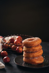 Stack of assorted donuts on a plate with milk on black background