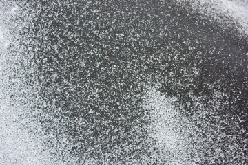 Bright white delicate and fluffy snowflakes are located on a black rubber background in winter.