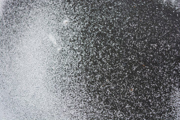Bright white delicate and fluffy snowflakes are located on a black rubber background in winter.