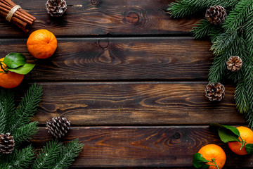 Tangerines near fir branches. New Year composition on dark wooden background top-down frame copy space