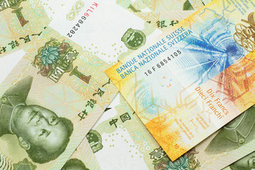 A yellow, ten Swiss franc note from Switzerland close up in macro with Chinese one yuan bills