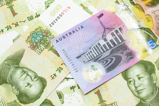 A close up image of an Australian five dollar bill with Chinese one yuan bank notes in macro