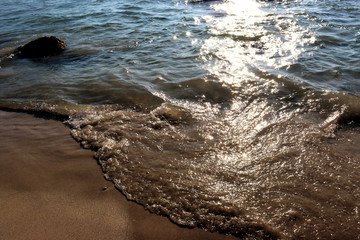 Beach idyll, sand and stones, bright sun glare on the waves