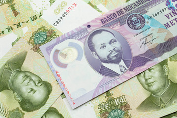 A close up image of a purple, twenty metical bank note from Mozambique on a background of Chinese...