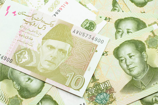 A close up image of an orange and ten Pakistani rupee bank note with Chinese one yuan bills in macro