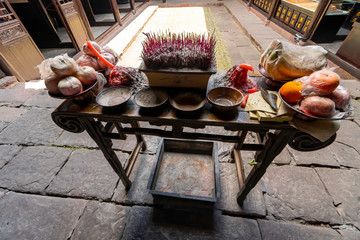 Fruit and incense on altar of offerings for the dead in a traditional inner courtyard, Yangjia Ancestral house.  Fenghuang Ancient Town, Hunan province, China