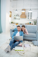 Smiling father and daughter looking at laptop screen.