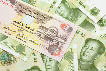A close up image of a five dirham bank note from the United Arab Emirates on a background of Chinese one yuan bank notes in macro