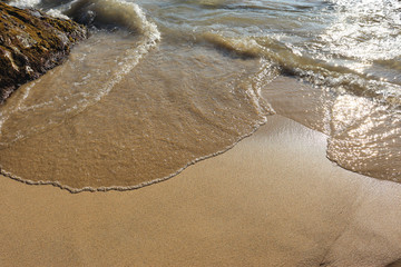 Beach idyll, sand and stones, bright sun glare on the waves