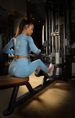 Fototapeta na wymiar Young adult woman doing exercises with weight machine