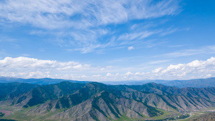 Aerial panoramic wide banner view of a Chike-Taman pass in the Altai mountains with green trees, Blue sky and clouds.