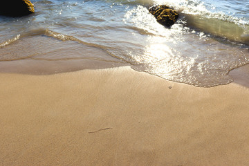 Beach idyll, sand and stones, bright sun glare on the waves
