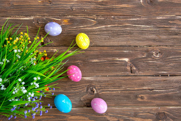 Happy Easter. Colorful easter eggs and flowers on wooden table. Top view with copy space