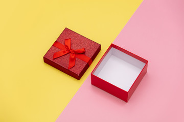 Little open gift box on pink and yellow backgrounds.