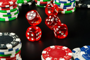 Dice and chips on black table close up