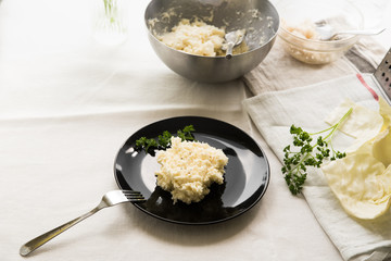 Chopped white cabbage salad with mayonnaise on a black plate