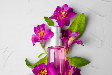 Bottle of fragrance or aromatic oil in a bunch of fresh flowers