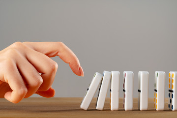 Woman hand toppling dominoes. Chain reaction business concept