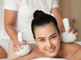 Beautiful young asian woman lying relaxing and smile on the bed having a massage with herbal...