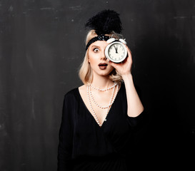 Beautiful blonde woman in twenties years clothes with alarm clock