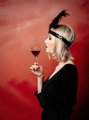 Beautiful blonde woman in twenties years clothes with cocktail