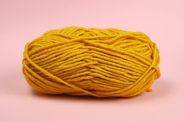 A tangle of mustard yellow threads on a pink background close-up