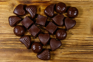 Heart shape made of different chocolate candies on wooden table. Top view. Valentine Day concept