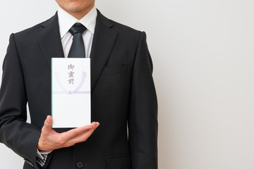 香典を持った喪服の男性