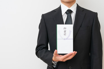 香典を持った喪服の男性