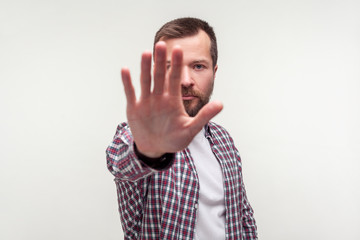 Stop! Portrait of bossy bearded man in casual plaid shirt holding out palm to camera, showing...