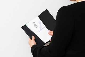 袱紗から香典を出す喪服の女性
