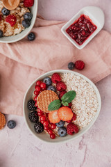 Oatmeal with berries in bowl on pink background
