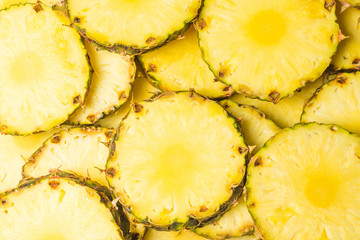 Pineapple juicy yellow slices background. Top view.