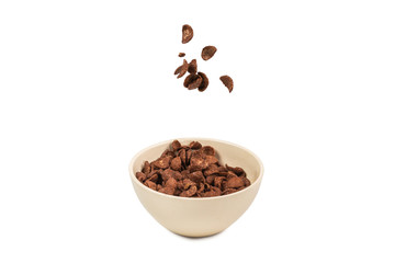 Chocolate corn flakes falling to the white bowl isolated on white. Motion.