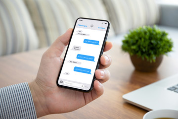 male hand holding phone with app messenger on the screen