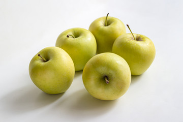 Five yellow-green apples on a light background