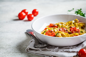 Green spinach pasta with tomatoes and herbs. Healthy vegan food concept.