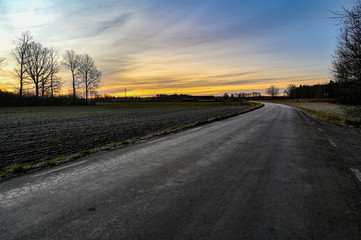 curved road through field with orange sunrise