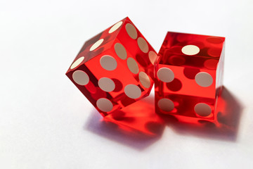 Two red glass dice on a gray background in sunlight. Result 1 and one on the edge, close-up with...