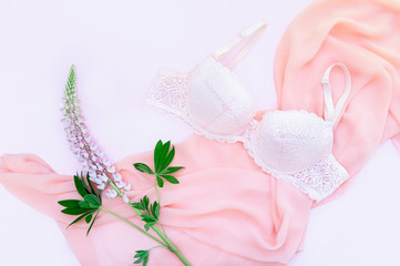 Delicate lace underwear on a pink background with pink lupine flowers. Pastel background. Flat lay, top view.