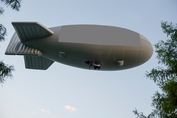 Flying Blimp with Signboard and Tree Branches with Blue Sky.