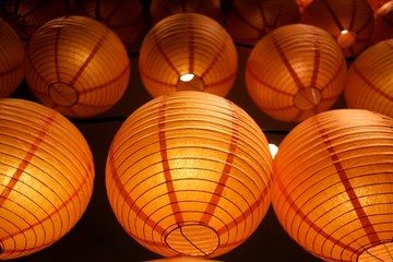 In selective focus a row of beautiful Chinese lanterns hanging on a wire with warm light and dark background 