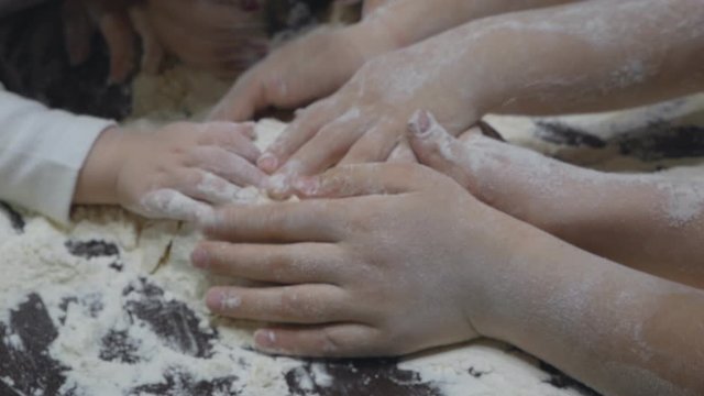 Close up Caucasian hands of mother and daughter making dough together. Slow motion