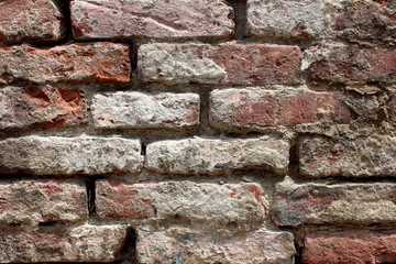 Cracked dilapidated suburban family house wall made of red bricks partially covered with concrete texture background wallpaper