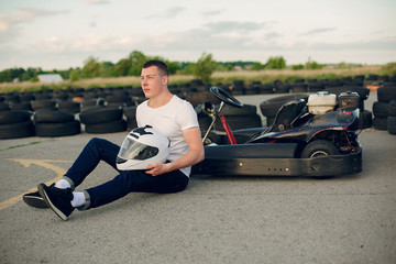 Fototapeta na wymiar Karting. Man in a white t-shirt. Male with a kart car